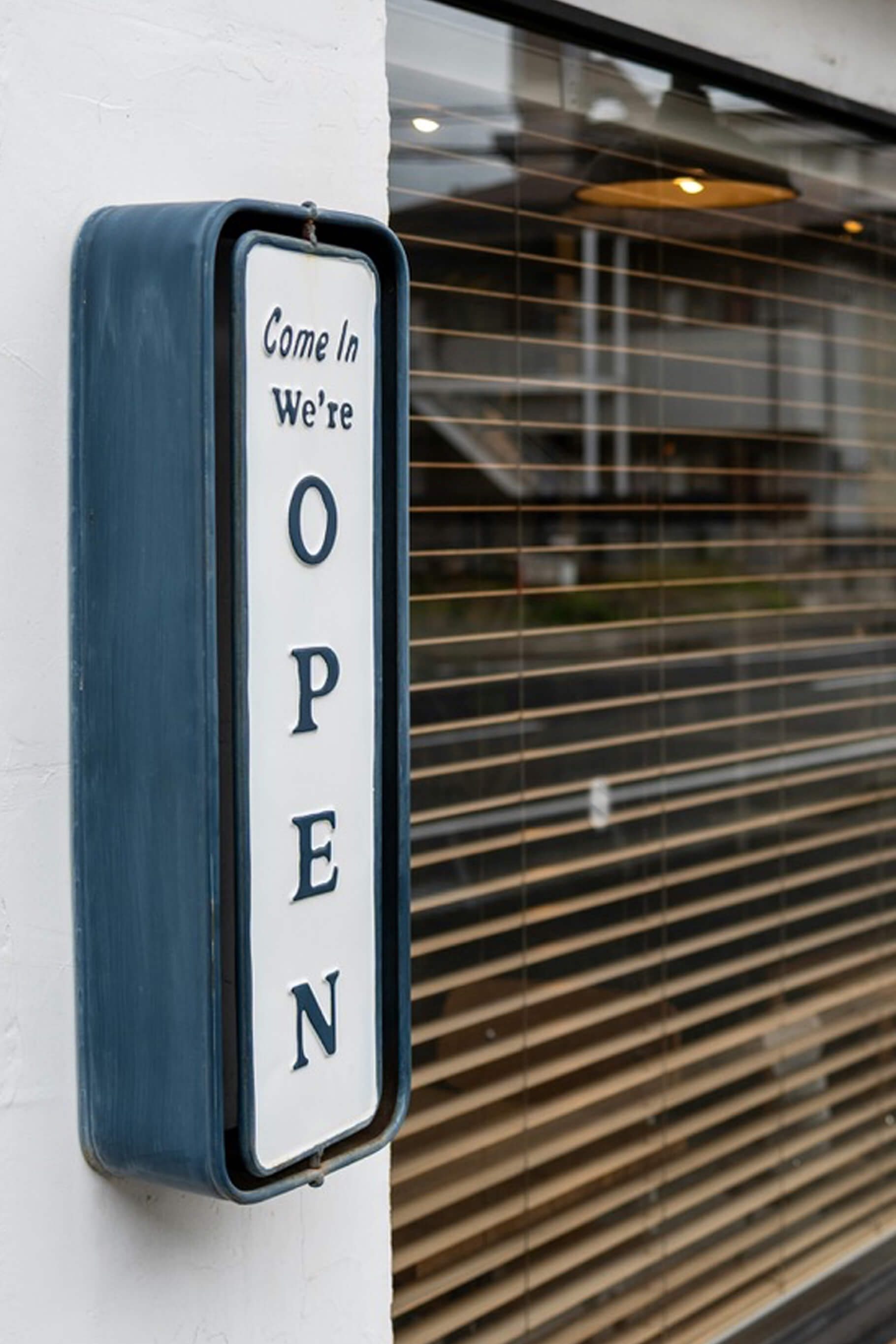 Open door with a "Come in, we're open" sign